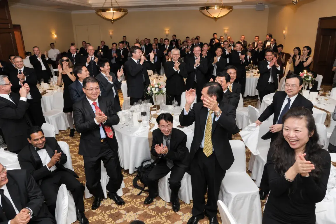 Guests in evening wear standing and applauding at a gala dinner premiere