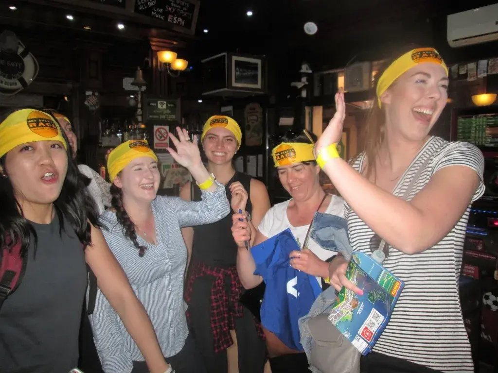 Laughing teammates in yellow headbands celebrating together in a lively bar